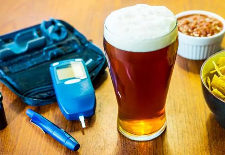 beer glass sitting beside diabetes testing equipment