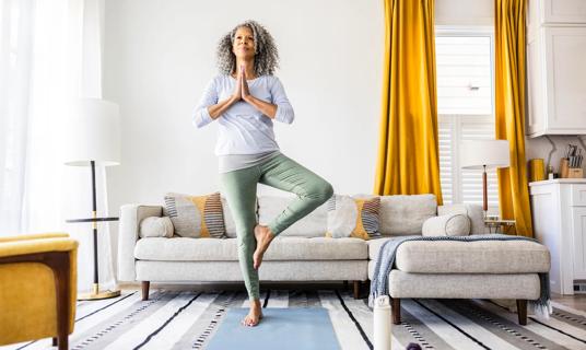 Person doing yoga tree pose in their living room
