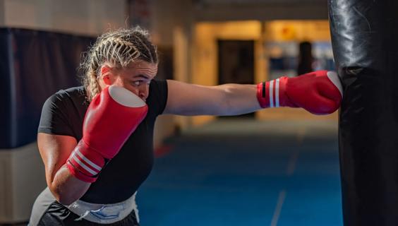 Person wearing boxing gloves punching a bag in gym