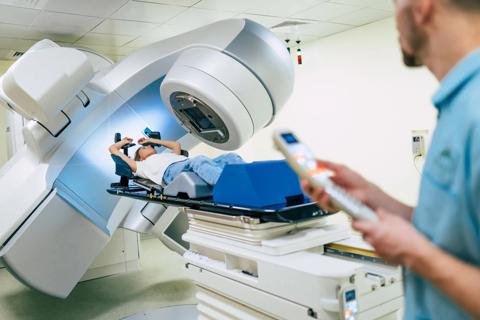 Person undergoing radiation therapy, with technician nearby