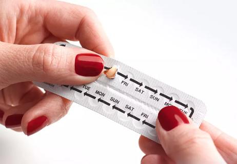 woman take birth control pill from packet