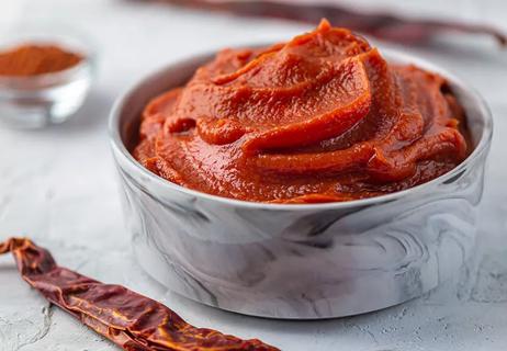 A silver bowl of reddish-brown colored sauce