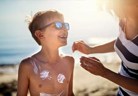 Mother applies sunscreen to son