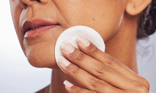 Person applying toner to their face with a cotton pad