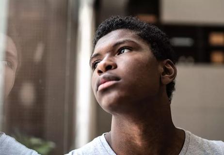 teen boy looking out window pensive