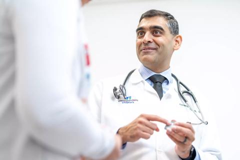 Physician holding wearable biosensor device talking to colleague