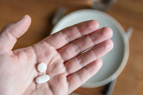 Open palm holding a white round pill and a white oblong tablet