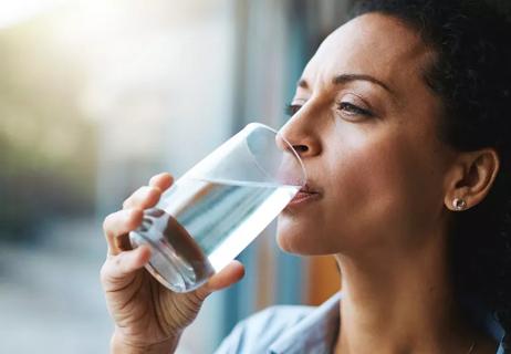 woman taking a drink of water to improve the taste in her mouth