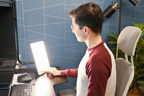 Person with a desk sun lamp facing them at their workstation