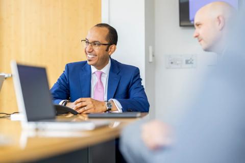 Man dressed in a suit sitting at a conference room table.