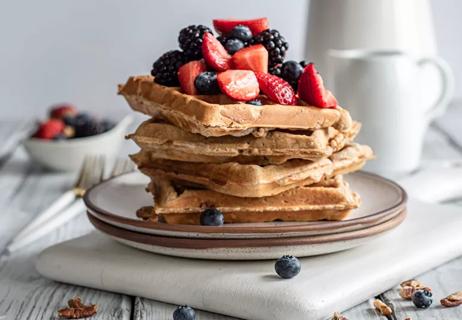 A stack of whole-wheat waffles topped by blueberries, strawberries and blackberries