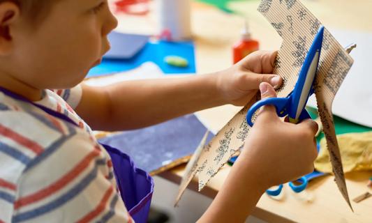 Young child using safety scissors on art project