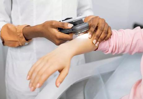 Dermatologist checking patient's arm.