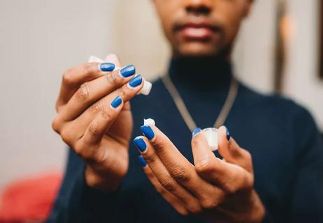 Closdup of person moisturizes painted fingernails.