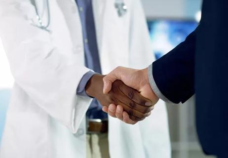 physician shaking hands with professional colleague