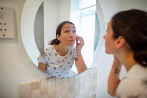 Person looking in mirror applying skin toner