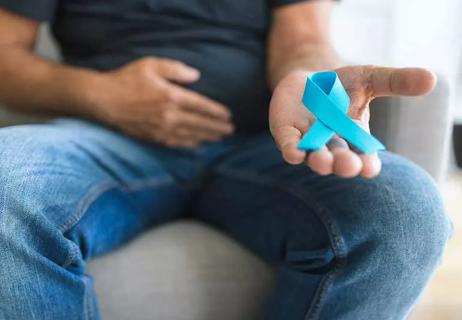 Man touching prostate surgery scar and holding cancer awareness ribbon.