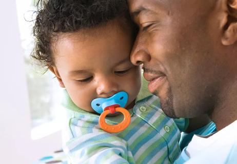 baby with pacifier held by daddy