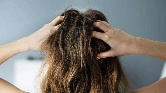 Back of person's head with long hair with hands scratching their scalp