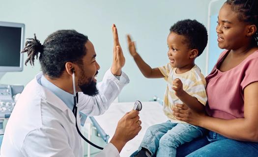 Healthcare provider high-fiving toddler sitting on caregiver's lap