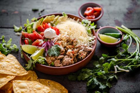 Taco salad with rice in a bowl and tortilla chips on the table