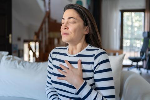 Woman sitting with hand on chest, taking deep breaths