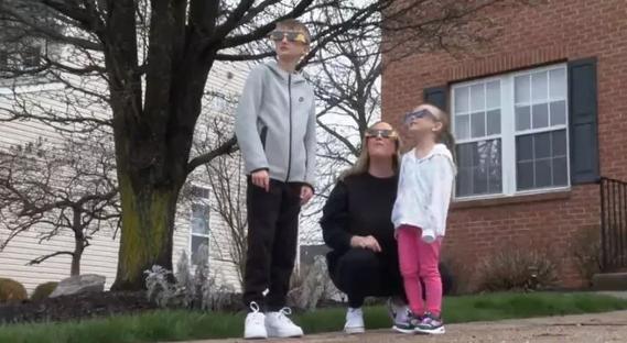 Family wearing protective solar eclipse glasses.