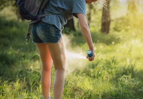 woman applying bug spray while on a hike