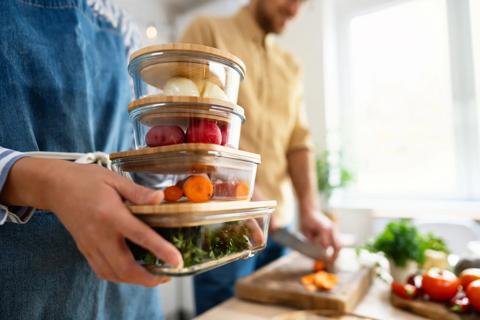 Couple in kitchen, with one holding prepped veggies in dishes
