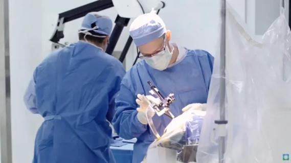 Surgeons performing a cerebrospinal procedure in an operating room.