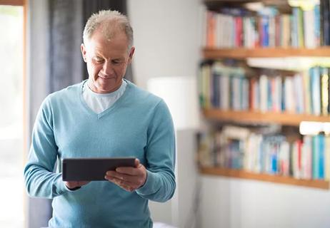 Senior man using tablet computer at home