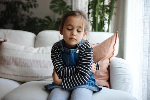 Young child sits holding stomach