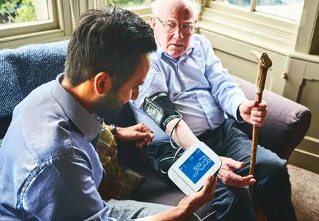 Person helps older family member with taking thier blood pressure.