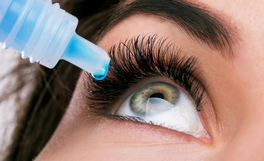 Eye drops being dropped into an adult's eye