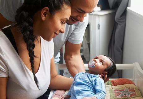Parents gaze lovingly on their newborn laying on the changing table.