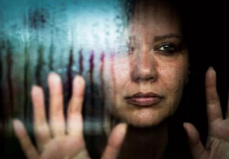 Closeup of person sick with grief staring out rainy window.