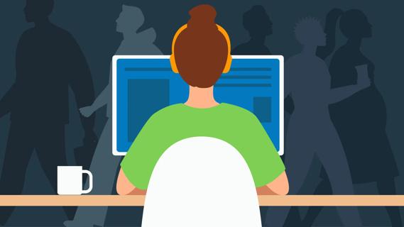 Person sitting at computer at desk, while others actively move about