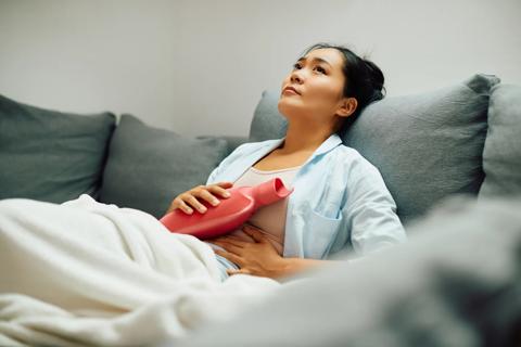 Woman reclining onwith hot water bag on abdomen