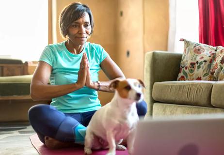 A woman sitting on the floor meditating with a cute dog in front of her