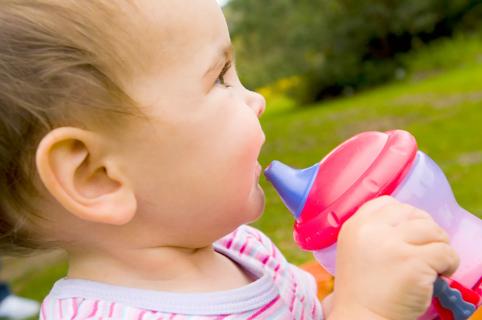Happy toddler holding sippy cup