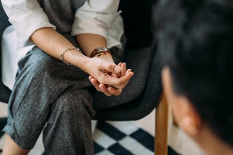 Close-up of hands of person sitting, legs crossed, facing another person