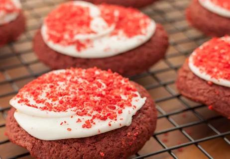 Fresh baked cookies using red dye with white frosting and red sprinkles