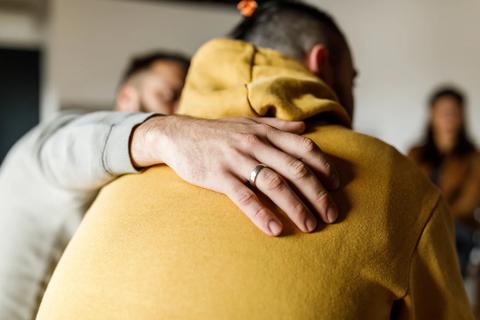 Person with arm around a participant’s shoulders, comforting them, at support group