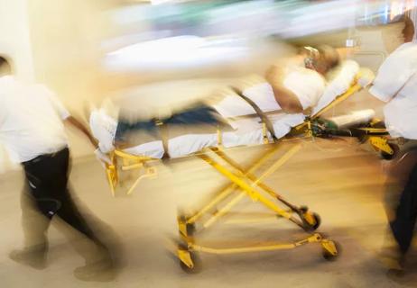man lying on a gurney being rushed through a hospital