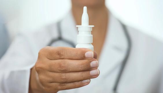 Healthcare provider holding up a nasal spray bottle