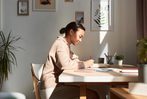 Person sitting at home desk writing in a journal