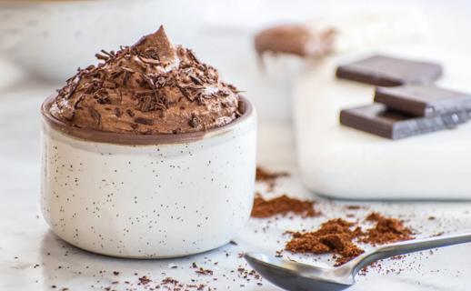 Chocolate espresso mousse in serving crock, with spoon, cocoa powder and chocolate nearby