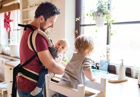 A parent with two children standing at a tabletop doing an activity