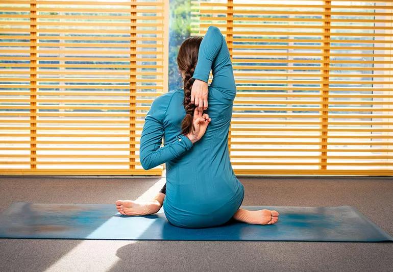 person on yoga mat in cow face pose