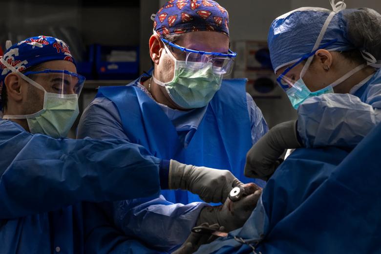 Three surgeons performing shoulder surgery in an operating room